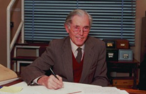 Geoffrey Rose sitting at his desk, pen in hand