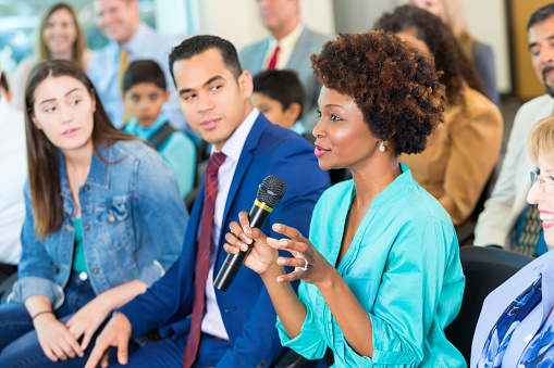 woman in audience speaking into microphone